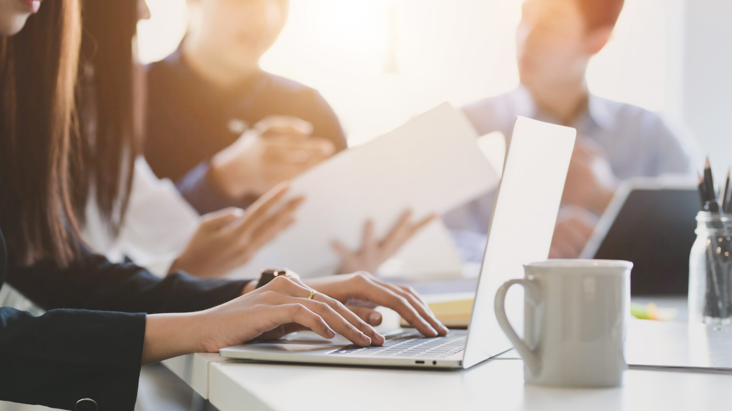Close up view of business people typing on computer laptop while working with her team